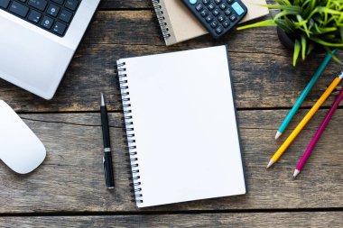 Akıllı telefonu ve bilgisayarı ahşap masa üstünde olan boş bir defter.