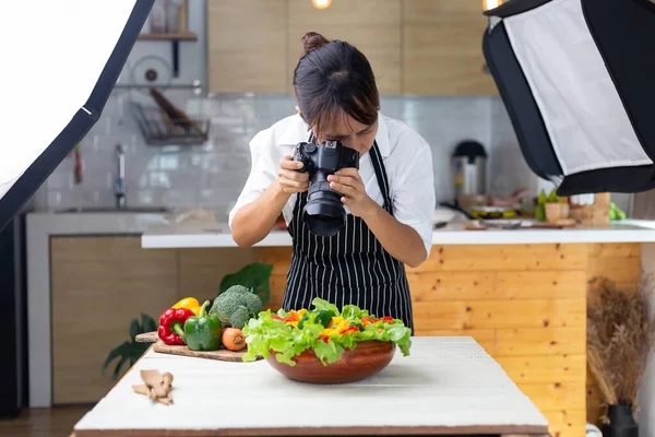 写真家の食べ物アジアの女性はスタジオで食べ物の写真を撮っています ストック写真