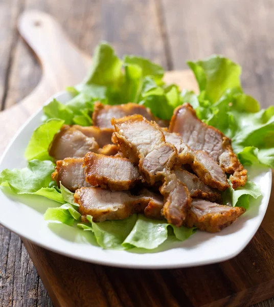 stock image Delicious fried pork in a white plate on a wooden chopping board