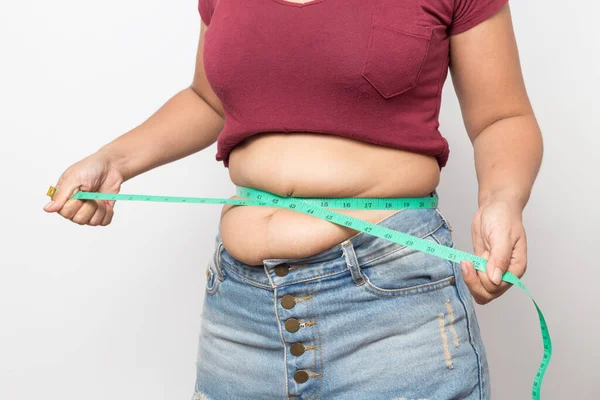 太りすぎの女性チェックアウト彼の体脂肪とともに緑測定テープのための肥満上の灰色の背景 健康的な概念 ストック画像