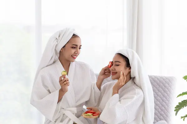 Asian female friends relax and spa massage with tomato facial mask in bathrobe. Spa, beauty, health massage. ,Thai aromatherapy spa treatments for women, body