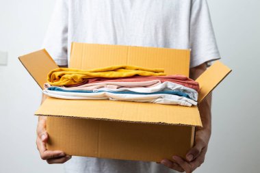 Bağış Konsepti, beyaz arka planda bağış kutulu giysiler tutan adam..