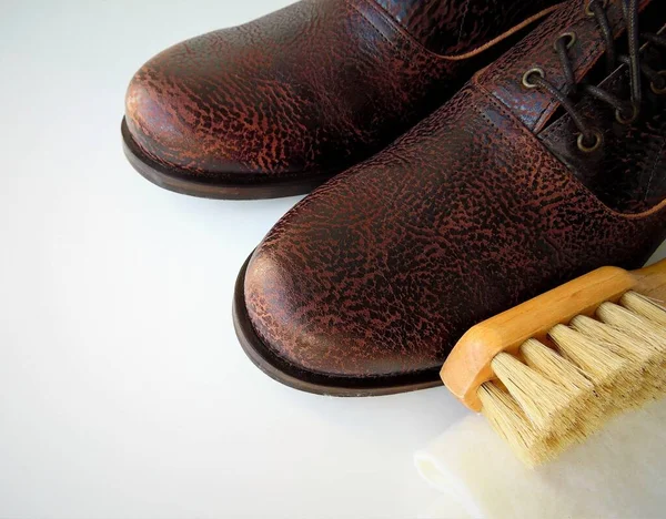 Men\'s  shoes and a brush for shoes on a light background. Leather shoe care, men\'s shoe cleaning