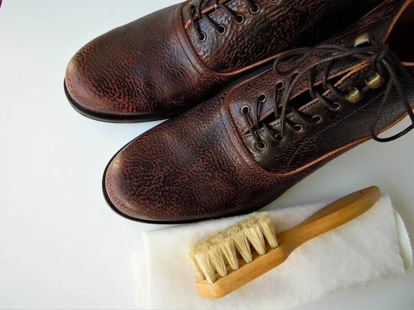 Men\'s  shoes and a brush for shoes on a light background. Leather shoe care, men\'s shoe cleaning
