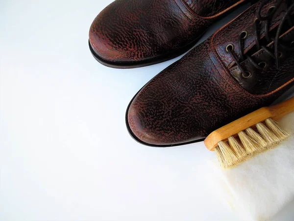 Men's  shoes and a brush for shoes on a light background. Leather shoe care, men's shoe cleaning
