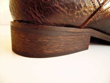 Açık arkaplanda klasik kahverengi bir ayakkabının topuğu.