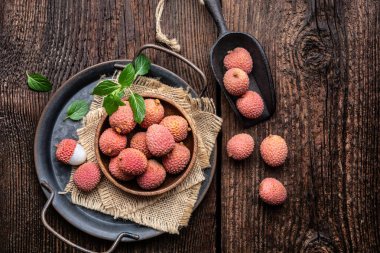 Tahta zemin üzerinde bir kase olgun tropikal lichee meyvesi (Litchi chinensis)