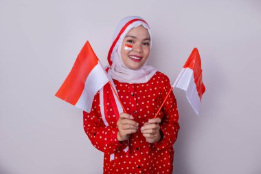 Kırmızı giysili tesettürlü bir kadın ve Endonezya bayraklı bir saç bandı Bağımsızlık Günü kutlamasında poz veriyor. Fotoğraf vatanseverliği ve ulusal gururu yansıtıyor..