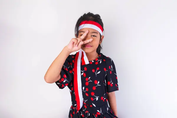 stock image A girl wearing an Indonesian flag headband and a black dress with a red pattern, posing with the theme of Indonesian Independence Day, reflects the spirit of patriotism.