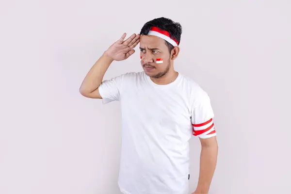 stock image An asian man in a white t-shirt outfit and a Indonesian flag headband poses in a celebration of Independence Day of Indonesian. The photo reflects patriotism and national pride.