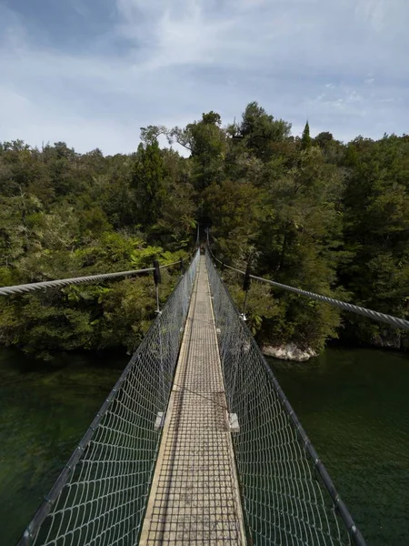 Empty cable suspension foot bridge spanning over river fresh water stream in Abel Tasman National Park South Island New Zealand
