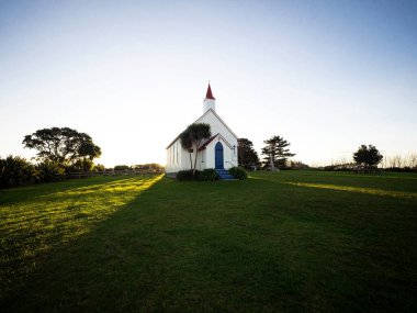 Old historic 19th century white presbyterian Awhitu Central Church with green grass during sunset on Manukau Heads Peninsula Auckland North Island New Zealand