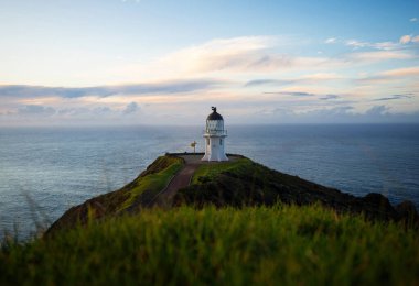Okyanus kıyısındaki kayalık Cape Reinga Aupouri Yarımadası Northland Kuzey Adası Yeni Zelanda 'da bulunan tarihi beyaz deniz fenerinin panoramik manzarası