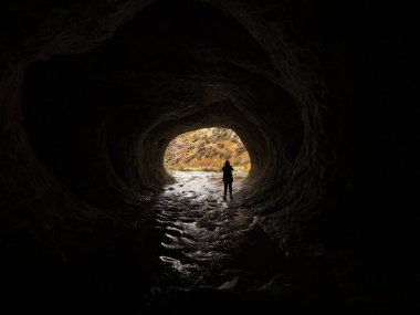 Canterbury Güney Adası Yeni Zelanda 'daki Broken River Mağara Akımı rezervindeki karanlık bir su tünelinde duran bir kişinin silüeti.