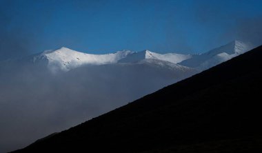 Alp dağlarının beyaz karla kaplı manzarası sisli bulut manzarasının üzerine bakan Güney Alp dağları 73. Eyalet Karayolu boyunca, Porter 'lar gözcü noktasından geçer, Canterbury Güney Adası Yeni Zelanda