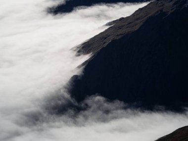 Alp dağlarının hava manzarası, bulutların üstündeki Güney Alpleri 'nin karla kaplı tepeleri, Yeni Zelanda Güney Adası Otago Southland.
