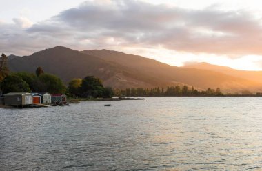 Grove Arm Jetty, Okiwa Körfezi, Kraliçe Charlotte Sound, Picton, Marlborough, Güney Adası, Yeni Zelanda 'daki renkli kayıkhanelerin gün batımı manzarası