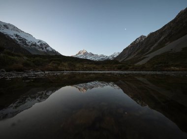 Kısmen donmuş göl aynasından yansıyan gölün yansıması Hooker Vadisi 'nden Cook Dağı Aoraki' nin görüntüsü, Canterbury Güney Adası Yeni Zelanda 'daki Güney Alp dağları karla kaplıydı.