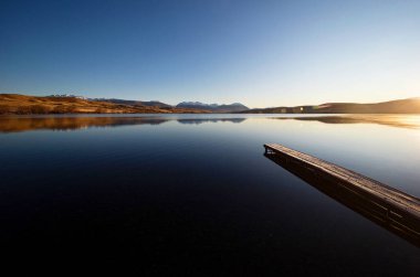 Idyllic sükunet gölü sakin Alexandrina teknesi iskelesi ahşap köprü sabahın erken saatlerinde güneş doğumu dağ manzarası Tekapo Canterbury Güney Adası Yeni Zelanda yakınlarındaki manzara