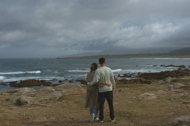 Yatay bir bakış açısıyla genç bir adam kollarını uzatarak denize bakan bir salıncakta yaz gününün özgürlüğünün tadını çıkarıyor. Pontes de Garcia Rodriguez olarak, La Coruna.