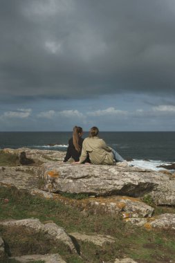 Yatay bir bakış açısıyla genç bir adam kollarını uzatarak denize bakan bir salıncakta yaz gününün özgürlüğünün tadını çıkarıyor. Pontes de Garcia Rodriguez olarak, La Coruna.