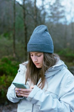 Paltolu ve şapkalı güzel bir bayan telefona bakıyor Preikestolen 'e giden yolu kontrol ediyor. Norveç 'te kış tatili.