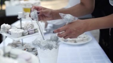 The waiter staff serves festival table candy, capcakes and macaruns. Luxury candy bar on white wedding