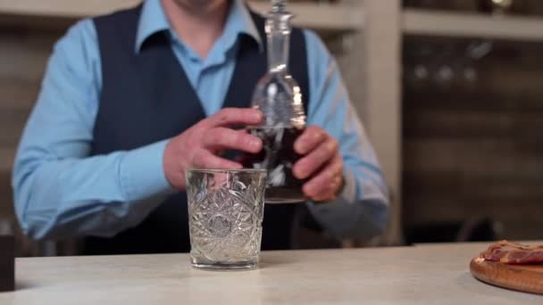 Bartender Blue Shirt Black Vest Stands Bar Takes Decanter Whiskey — Vídeos de Stock
