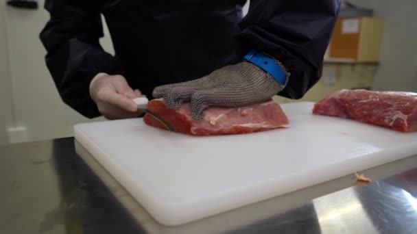 屠夫戴上金属防护手套 用刀具在切碎的白板上切下一块新鲜的生肉 靠近点 — 图库视频影像