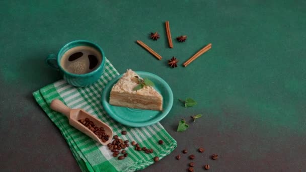 新鲜美味的拿破仑蛋糕 绿色背景的奶油 一杯热咖啡 肉桂棒 八角豆 绿底咖啡豆 复制空间 — 图库视频影像