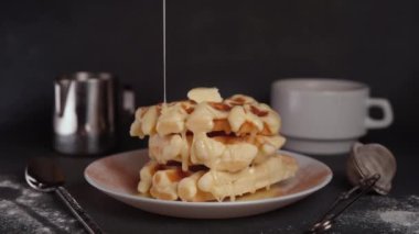 Pasta Şefi karamel şurubu, lezzetli waffle, karamel sosu, kahve fincanı, süt, tatlı kaşığı, siyah beton arka planda süzgeç