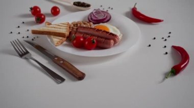 İngiliz Kahvaltısı. Kızarmış yumurta, iki kızarmış sosis, kızarmış ekmek tostu, konserve fasulye, mavi soğan ve beyaz arka planda vişneli domates. İngiliz kahvaltısı konsepti. Metin için alanı kopyala