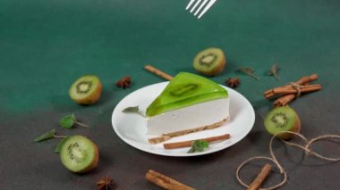 Çatallı Man 's Hand, Kiwi ile Cheesecake' in bir parçasını kırıyor. Tarçın çubukları, badyan, yeşil arkaplanda nane yapraklarıyla süslenmiş.