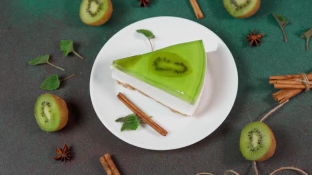 自制芝士蛋糕 基维在一个白色的盘子绿色背景 用奇异果片 肉桂棒和薄荷叶洗净 — 图库视频影像
