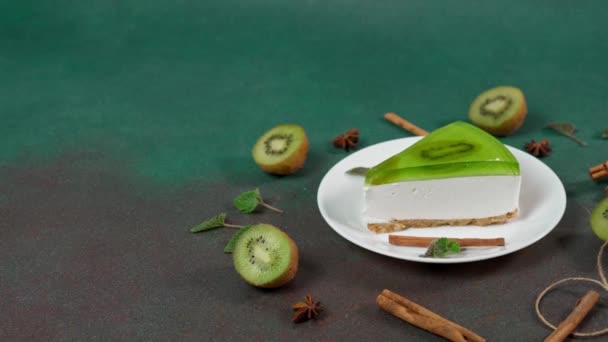 自制芝士蛋糕 基维在一个白色的盘子绿色背景 用奇异果片 肉桂棒和薄荷叶洗净 复制空间 — 图库视频影像