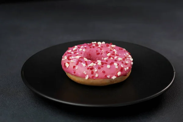 Розовый Глазированный Пончик Красочными Брызгами Черной Тарелке Розовый Пончик Черном — стоковое фото
