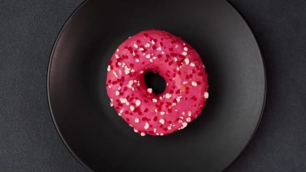 Вид Сверху Розовый Орех Цветным Посыпанием Черной Тарелке Розовый Пончик — стоковое видео