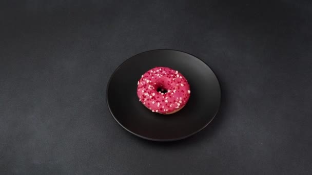 Pink Mengkilap Doughnut Dengan Percikan Berwarna Warni Atas Piring Hitam — Stok Video