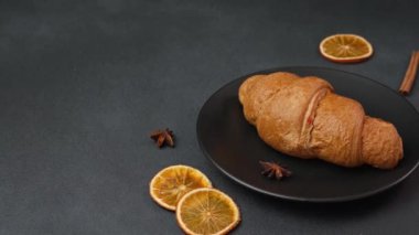 Lezzetli, yeni pişmiş kruvasan siyah bir arka planda siyah bir tabakta yatıyor.