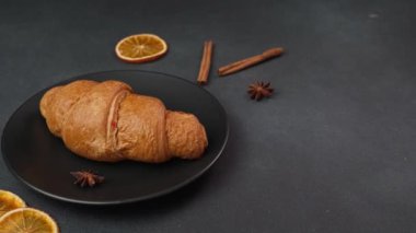 Lezzetli, yeni pişmiş kruvasan siyah bir arka planda siyah bir tabakta yatıyor.