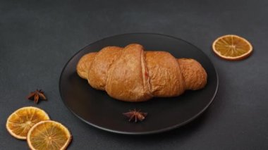 Kafkas Adam 'ın Eli' nin yakın çekimi yeni pişmiş kruvasan siyah arka planda, siyah tabakta yatıyor.