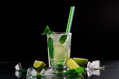 Mojito Kokteyli 'ni limon, buz küpleri ve siyah arkaplanda yeşil nane yapraklarıyla tazelemek