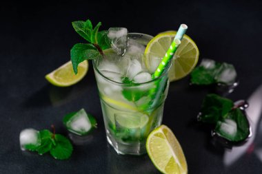 Mojito Kokteyli 'ni limon, buz küpleri ve siyah arkaplanda yeşil nane yapraklarıyla tazelemek