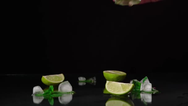 酒保手拿起一杯Mojito放在桌上的特写镜头 桌上放着石灰 朗姆酒和绿色薄荷 背景是黑色的 — 图库视频影像