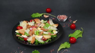Tavuklu Sezar Salatası, marul yaprakları, kiraz domatesleri, siyah bir tabakta rendelenmiş parmesan...