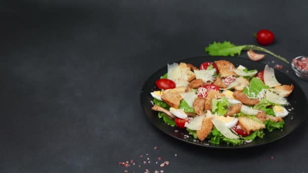 凯撒沙拉 生菜叶 樱桃西红柿 烤意大利面在一个黑色的盘子与黑色背景 — 图库视频影像