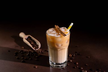 Buzlu kapuçino, uzun bir bardakta siyah arka planda. Sütlü buzlu kahve.