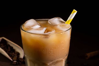 Kapuçinonun kapuçinosu, uzun bir bardakta buzla kaplanmış, siyah bir arka planda. Sütlü buzlu kahve.
