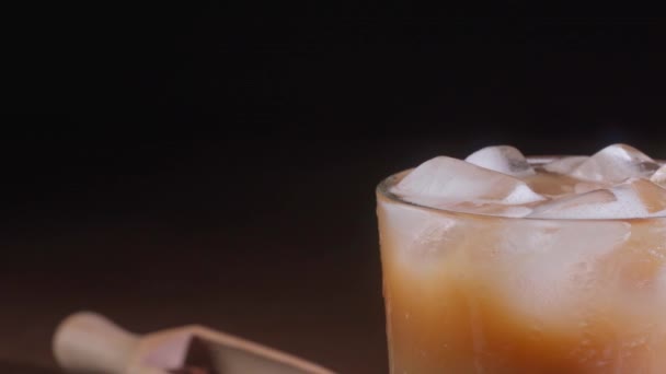 卡布奇诺的特写镜头 在一个黑色背景的高玻璃杯里放着冰块 一杯加奶的冰镇咖啡 — 图库视频影像