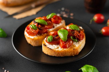 Ricotto peyniri ve vişneli domates fesleğen, siyah arka planda sarımsak. Yiyecekler. Gıda arkaplanı